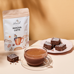 Nomad Chocolate Mocha Latte, dark cacao with instant coffee, smooth and delicious, gluten free, dairy free, vegan. Plant based. Drink in a glas cup with scrumptious brownies.