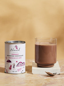 Nomad Chocolate Organic Drinking Chocolate Dominican 55% Dark tin next to hot chocolate in glass