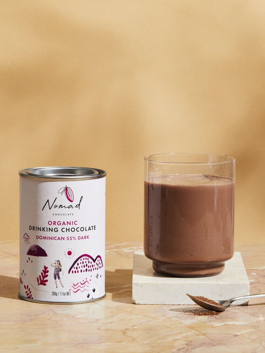 Nomad Chocolate Organic Drinking Chocolate Dominican 55% Dark tin next to hot chocolate in glass