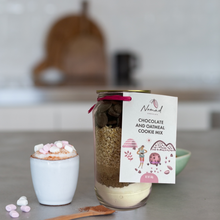 Load image into Gallery viewer, nomad chocolate and oatmeal cookie mix in the jar on the kitchen bench top with hot chocolate