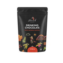 Load image into Gallery viewer, A black stand-up pouch of Nomad Chocolate Drinking Chocolate with Australia Natives, featuring white and orange text and colorful illustrated botanical and human elements on a white background.