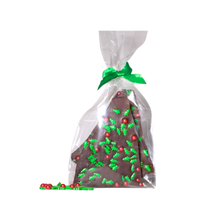 Load image into Gallery viewer, Image of Nomad chocolate bark topped with candies in the shape of Christmas tree and round balls. Packed in cellophane bag with the green bow tie