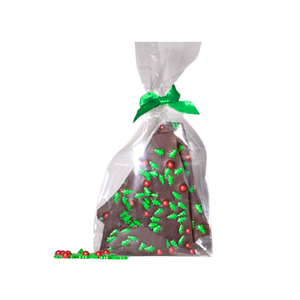 Image of Nomad chocolate bark topped with candies in the shape of Christmas tree and round balls. Packed in cellophane bag with the green bow tie