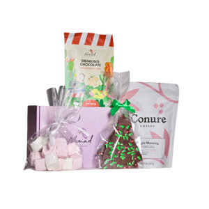 Image of Nomad Chocolate gift box in purple, Nomad Hot chocolate peppermint candy 140g in a pouch bag, Conure Coffee bright morning coffee beans in 250g bag, cellophane bag with pink and white big marshmallows and Nomad Chocolate bark packed in cellophane bag with Christmas toppings in a shape of green Christmas tree and red balls