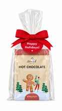 Load image into Gallery viewer, A packaged bag of Nomad Chocolate Hot Chocolate Gingerbread, wrapped in clear cellophane with a large red ribbon and a red 'Happy Holidays!' tag, on a white background.