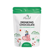 Load image into Gallery viewer, A stand-up pouch of Nomad Chocolate Drinking Chocolate with Peppermint Candy, featuring a white bag with a bright green top and a green bottom band, decorated with illustrations of candy canes, hills, and a person sitting on a large candy cane.