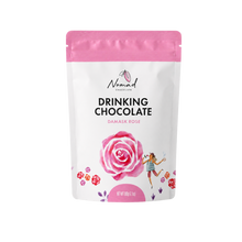 Load image into Gallery viewer, A stand-up pouch of Nomad Chocolate Drinking Chocolate in Damask Rose flavor, featuring a white package with a pink top band, a large pink rose illustration, and a small dancing woman graphic.