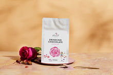 Load image into Gallery viewer, Nomad Dark hot chocolate Rose with pink rose next to bag